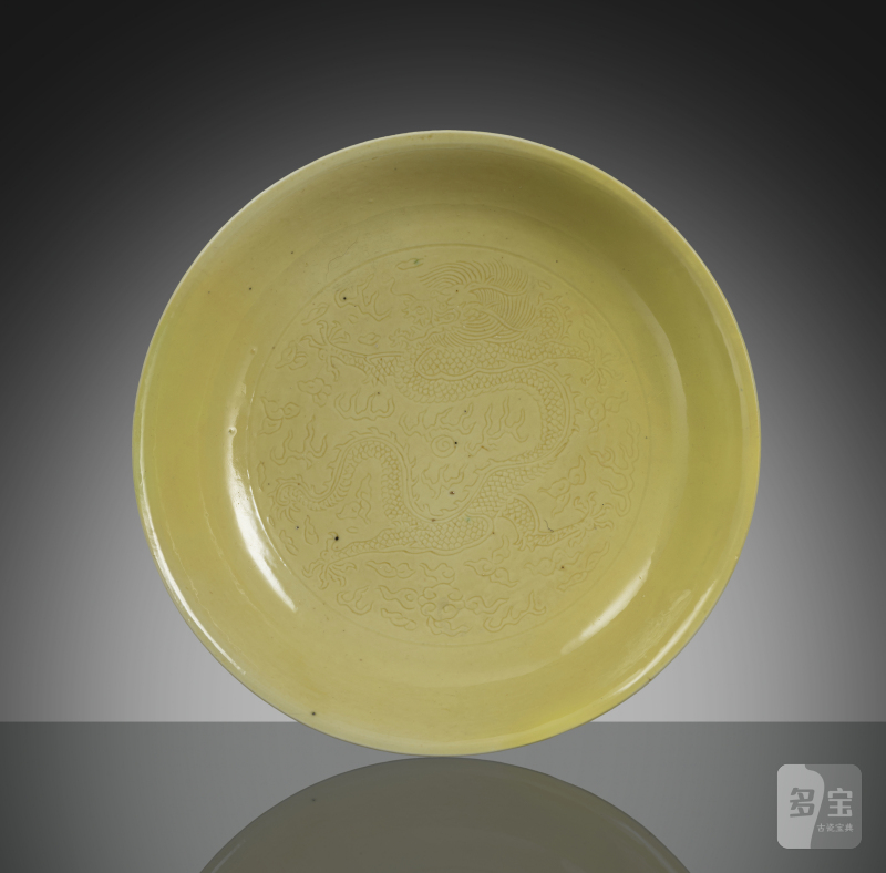 An imperial yellow glazed porcelain plate with engraved decoration of dragons and flaming pearls